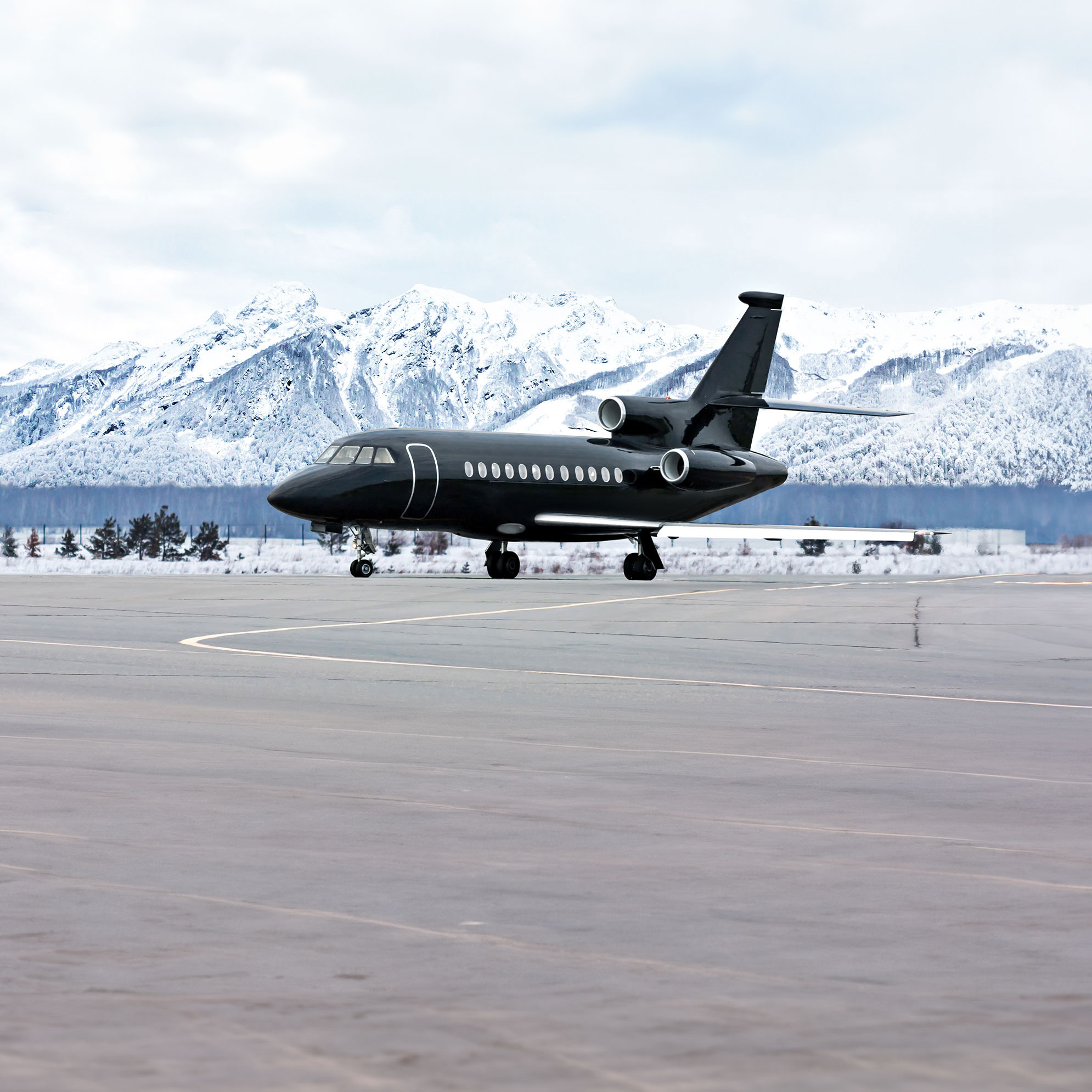 Private jet on a runway against snow-capped mountains